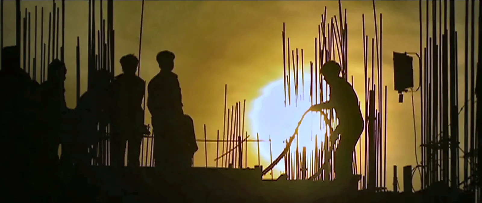 Construction workers silhouetted against the setting sun at an IRCON project site, from the IRCON corporate film