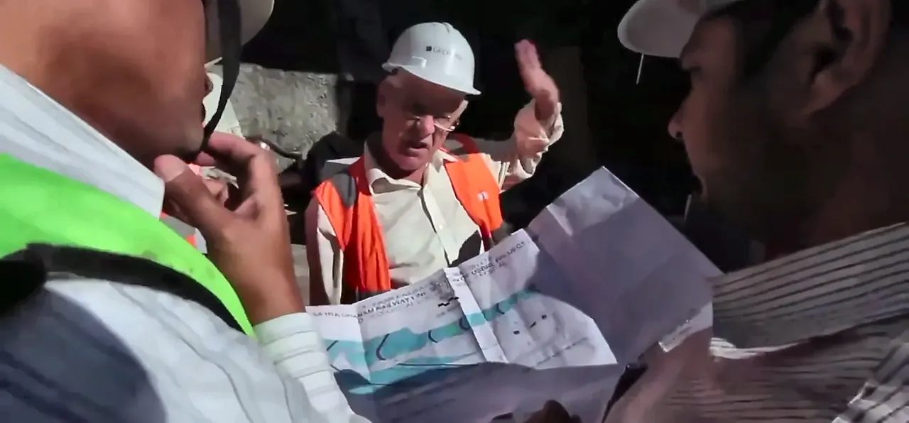 Engineers in hard hats reviewing a railway alignment plan on site, from the IRCON International film