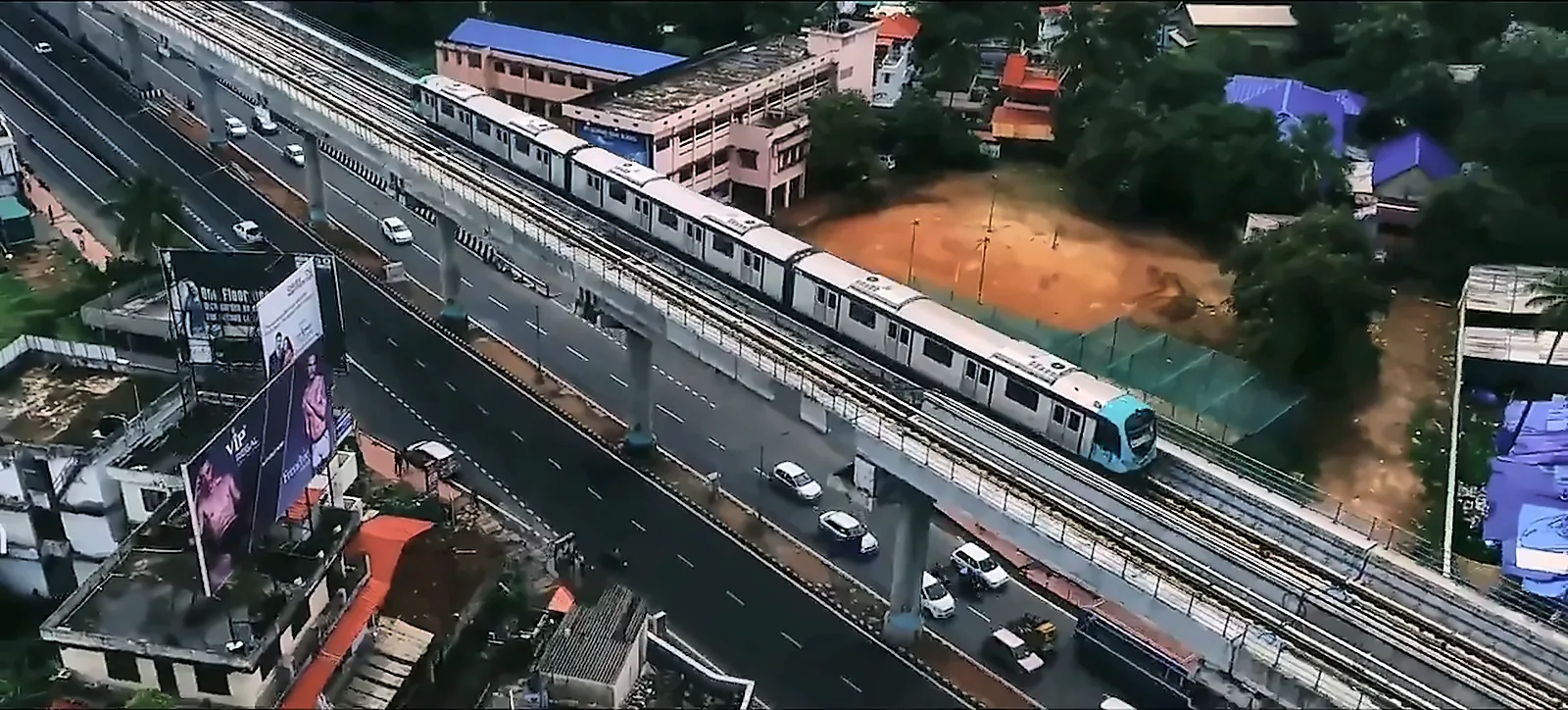 Aerial drone shot of a metro train on an elevated viaduct above city traffic, from the IRCON International corporate film