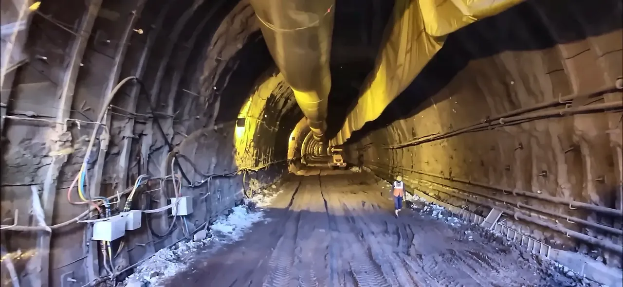 Worker in a safety vest walking through a lit railway tunnel under construction, from the IRCON corporate film