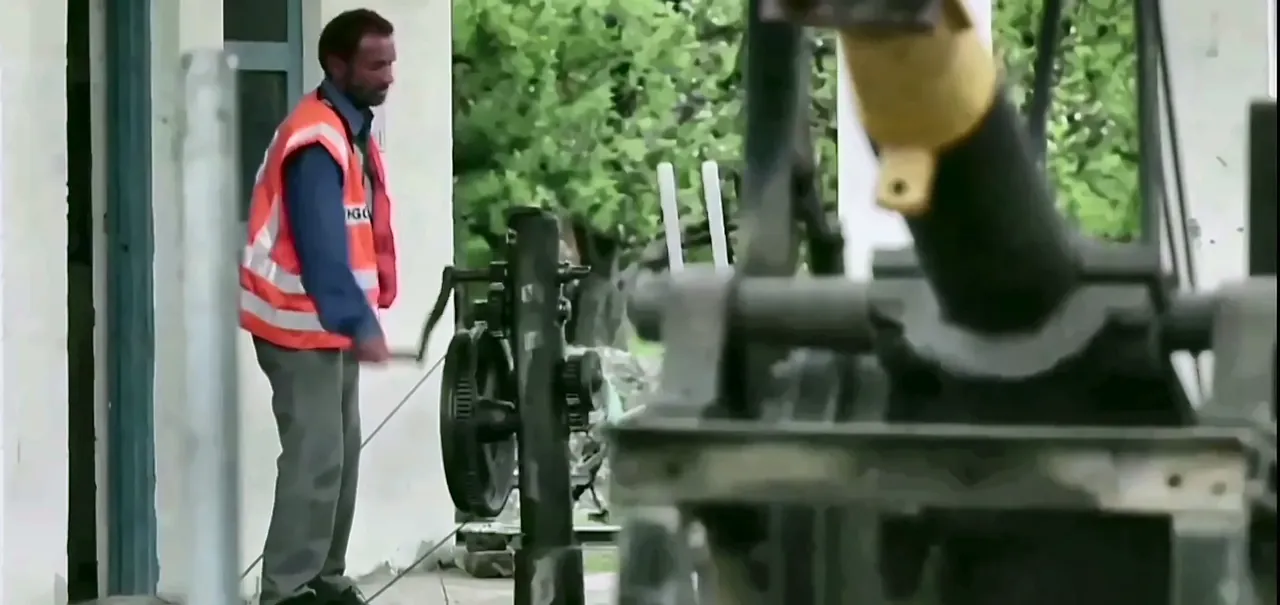 Railway worker in a safety vest operating a manual lever at a station, from the IRCON International film