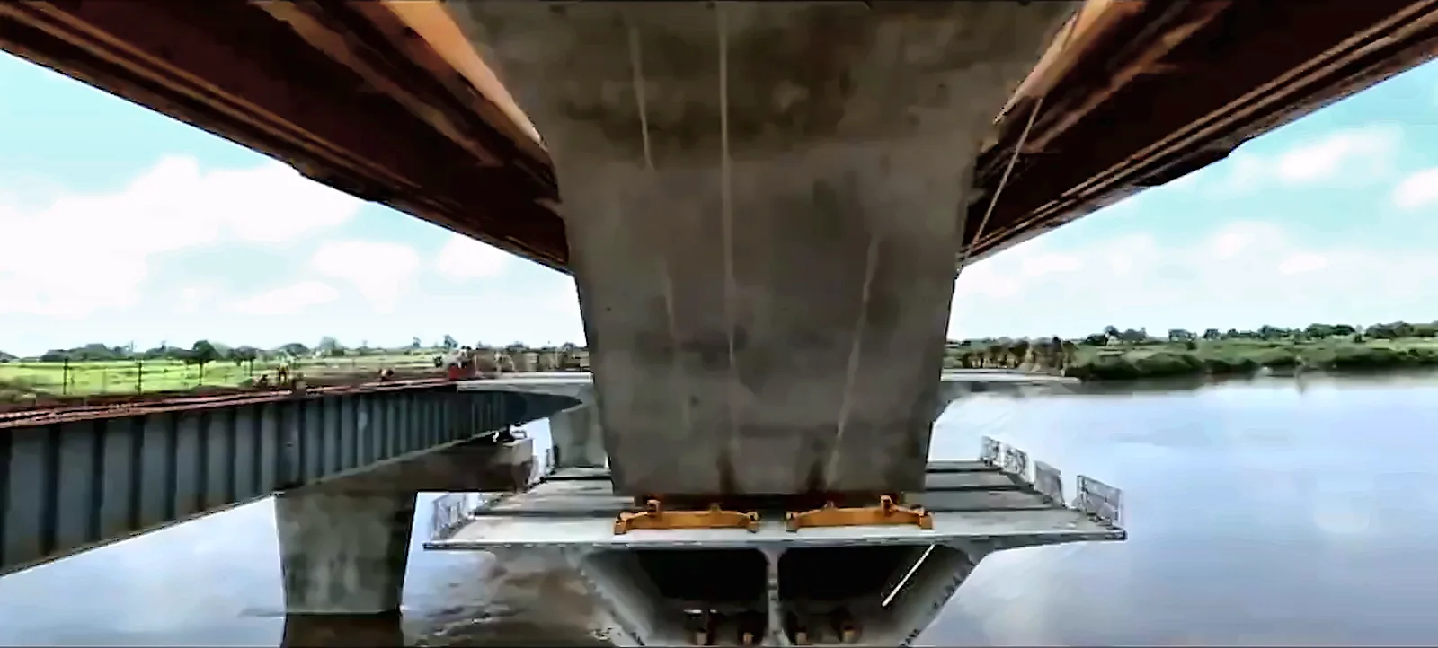 View from beneath a concrete river bridge with a steel girder bridge alongside, from the IRCON International corporate film
