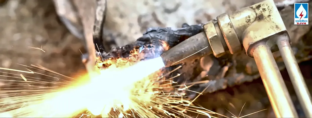 Close-up of gas cutting with sparks at an SJVN project site, from the SJVN corporate film