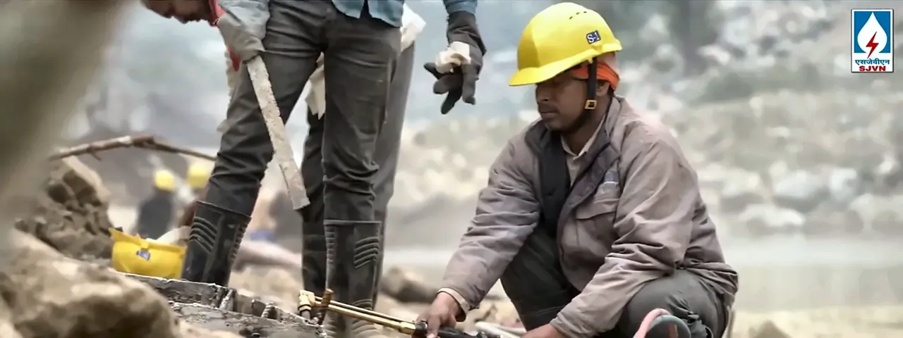 Worker in a yellow helmet doing gas cutting at an SJVN hydro project site