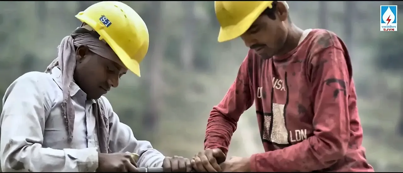 Two workers in yellow helmets working together at an SJVN project site